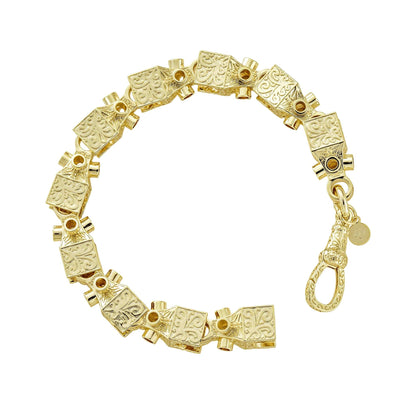 Close-up of gold geometric bracelet with intricate patterned links.